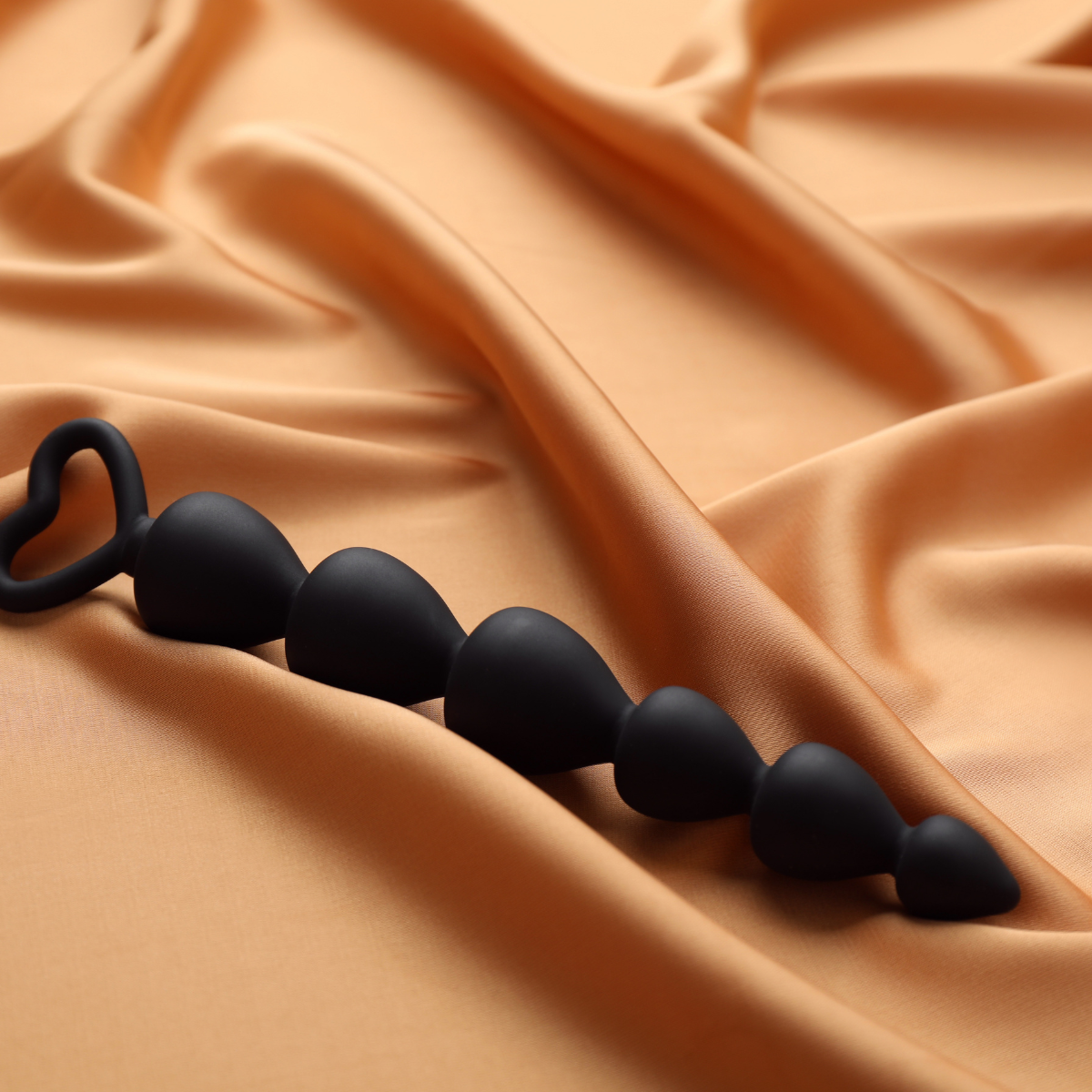 Black anal bead on orange fabric.    Discover pleasure products in Trinidad and Tobago from Belle Exotics, including couple toys, lubricants, lingerie, and beginner-friendly adult products.