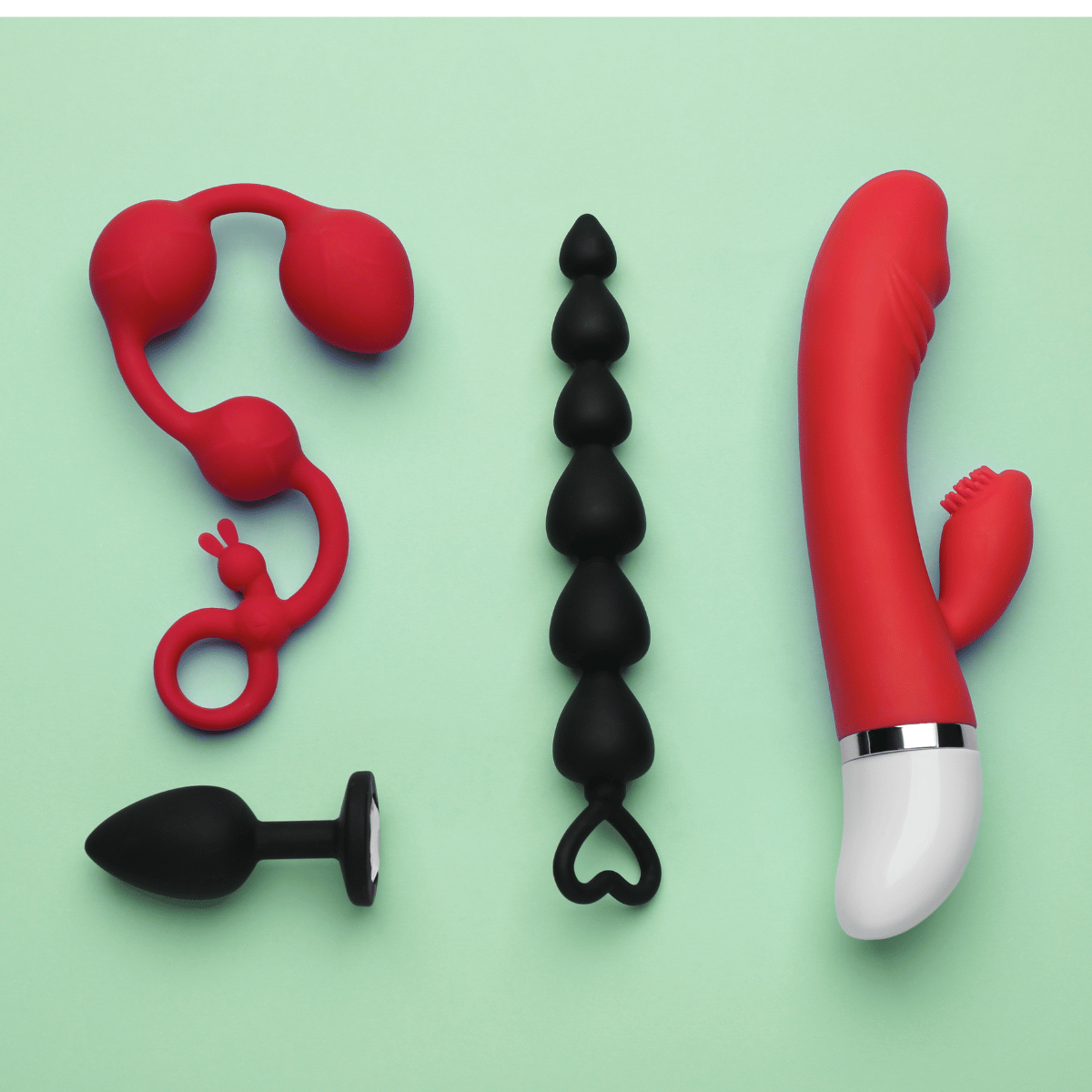 Collection of red and black silicone toys on a green background.Promotional image for a Belle Exotics Anniversary with text overlay and a person in a white dress.Promotional advertisement for a Trinidad & Tobago pleasure store with text and a person in a yellow top. Anniversary Campaign  by Belle Exotics in Trinidad and Tobago promoting confident exploration, sexual wellness, and guided intimacy in-store and online.