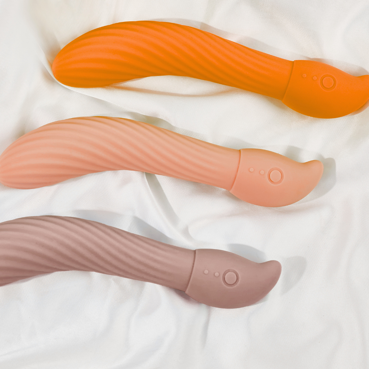 Three silicone tools in orange, pink, and gray on a white fabric background.Woman sitting on a vintage car holding flowers, with a building and sign in the background.    Discover pleasure products in Trinidad and Tobago from Belle Exotics, including couple toys, lubricants, lingerie, and beginner-friendly adult products.