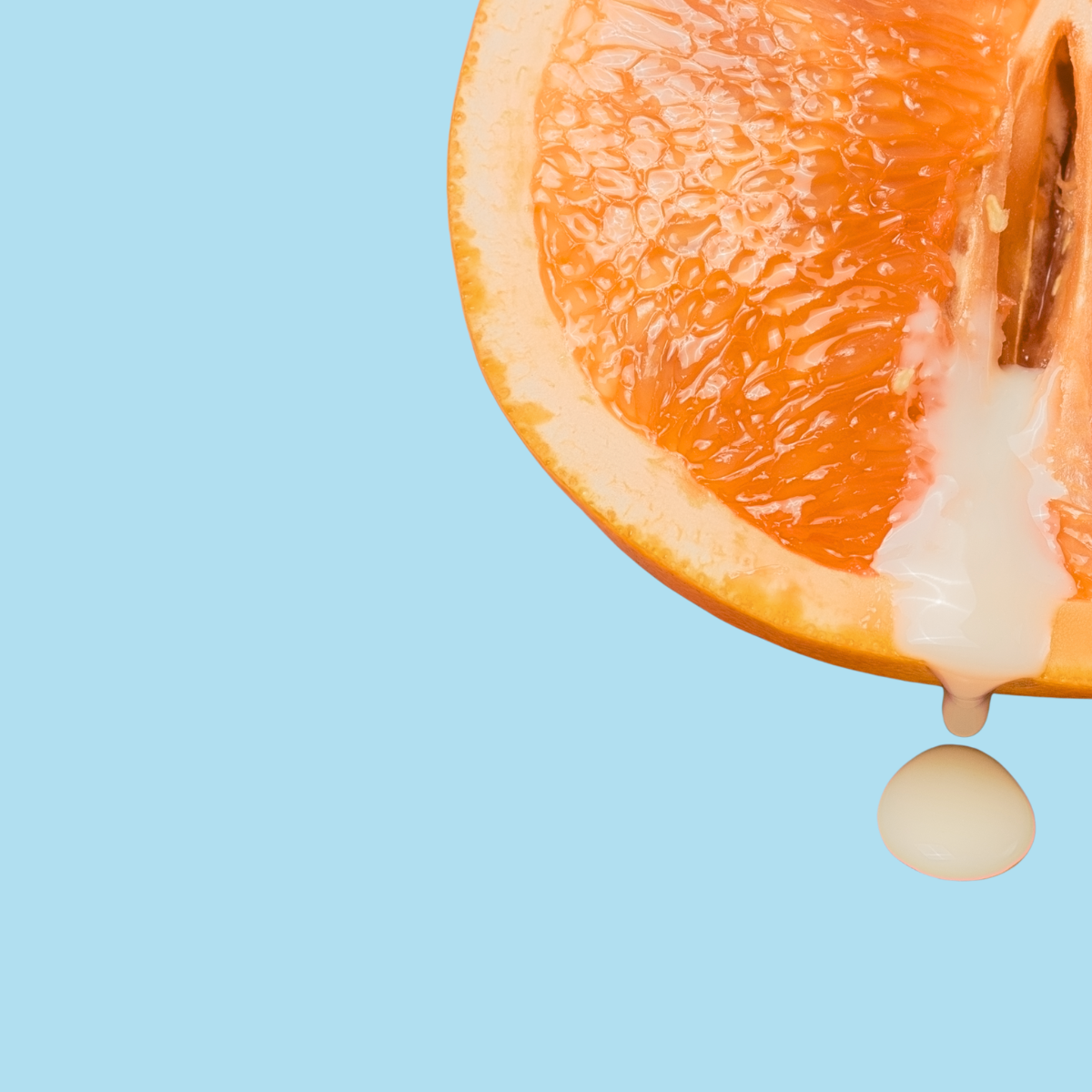 Close-up of a sliced grapefruit with a drop of juice on a light blue background. Discover Pleasure & Sensuality at Belle Exotics. Elevate intimacy with our luxury collection of pleasure products. Shop online or visit our Trinidad store for an extraordinary experience. Ignite your senses today.