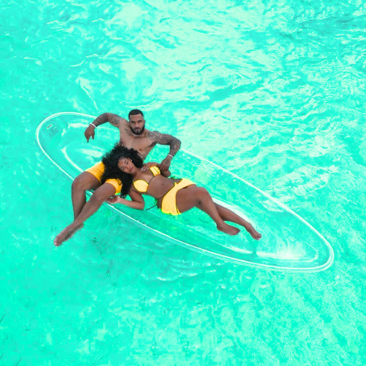 Two people lying on a clear inflatable raft in a pool with turquoise water.Belle Exotics offers luxury adult toys and sexual wellness products in Trinidad and Tobago, designed for pleasure, confidence, and discreet delivery.